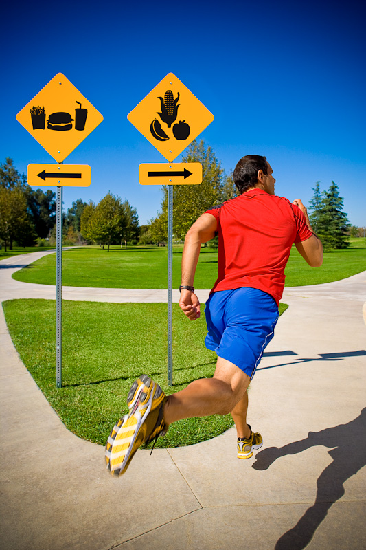 Runner passing two signs of food, one sign of junk food and the other of healthy food, the runner choosing to go the direction of Healthy Food